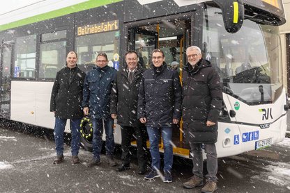 Fünf Personen vor Wasserstoffbus mit Schneetreiben